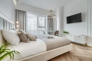 een witte slaapkamer met een groot bed en een televisie bij Apartament Ariela LUX 17th fl HANZA in Szczecin