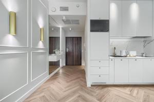 een keuken met witte kasten en een houten vloer bij Apartament Ariela LUX 17th fl HANZA in Szczecin