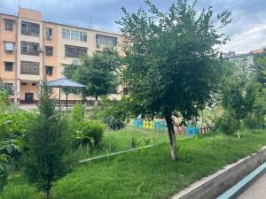 a garden with a tree and an umbrella in front of a building at APARTMENT “NOVZA” in Tashkent