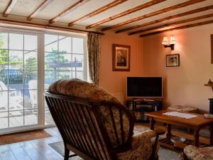 a living room with a chair and a table and a television at Cider Press Cottage in Blakeney