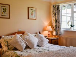 a bedroom with a bed with white pillows and a window at Cider Press Cottage in Yorkley