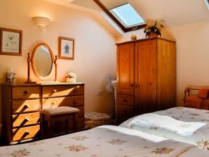 a bedroom with two beds and a dresser and a mirror at Cider Press Cottage in Yorkley