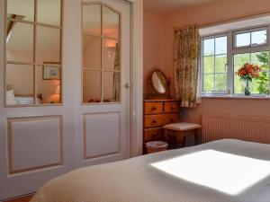 a bedroom with a bed and a window and a mirror at Cider Press Cottage in Blakeney