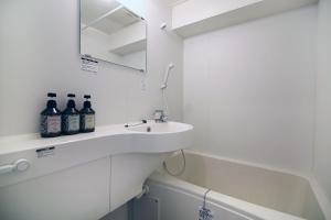 a white bathroom with a sink and a mirror at GM Shinjuku in Tokyo