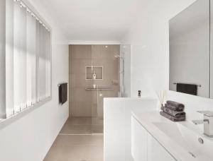 ein weißes Bad mit einer Dusche und einem Waschbecken in der Unterkunft Guest House On Guy in Forster