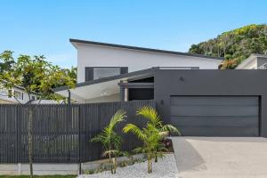 a white house with a black fence and palm trees at Coast in Lennox Head