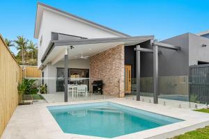 a house with a swimming pool in front of a house at Coast in Lennox Head