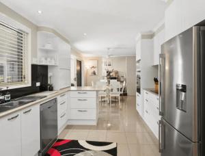 Una cocina con gabinetes blancos y un refrigerador de acero inoxidable. en Guest House On Guy, en Forster