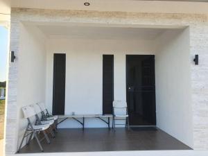 d'une terrasse avec des chaises et une table sur un mur blanc. dans l'établissement Executive Two Bedroom Villa For Hire in Nadi, à Nadi