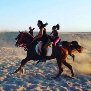 a group of people riding horses on the beach at Happy Bedouin House Petra in Al Ḩayy