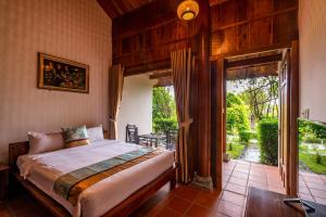 a bedroom with a bed and a door to a patio at Maison Du VietNam Resort & Spa in Phu Quoc