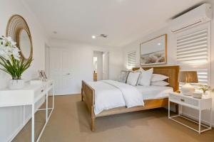 a white bedroom with a large bed and a desk at By the beach 2 beach side 3 bedroom 2 bathroom home in Alexandra Headland