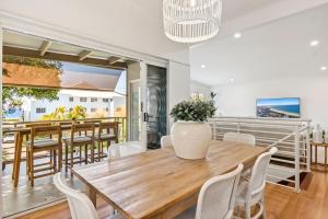 a dining room with a wooden table and white chairs at By the beach 2 beach side 3 bedroom 2 bathroom home in Alexandra Headland