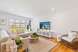 a living room with a couch and a table at By the beach 2 beach side 3 bedroom 2 bathroom home in Alexandra Headland