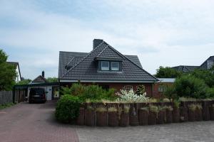 une maison avec une clôture devant elle dans l'établissement Haus Kölfhamm, à Sankt Peter-Ording