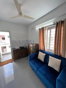 a blue couch in a living room with a ceiling fan at StayhomeStays Prime in Bangalore