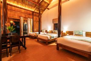 una camera da letto con due letti e una scrivania in una stanza di Maison Du VietNam Resort & Spa a Phu Quoc
