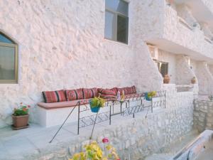 a stone walled patio with a red couch at Infinity Lodge in Wadi Musa