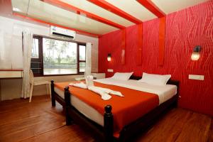 a bedroom with a red wall with a bed and a window at JCT Houseboat in Alleppey