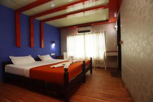a bedroom with a bed with an orange and blue wall at Harmony Houseboats in Alleppey