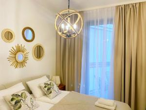 1 dormitorio con cama y lámpara de araña en Apartament BOHO SUMMER 71 Z Widokiem Na Morze - 365PAM, en Ustronie Morskie