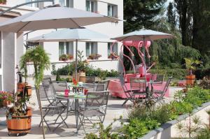 a patio with tables and chairs and umbrellas at Auberge Du Parc in Baudricourt