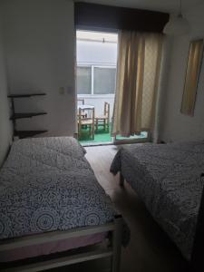 a bedroom with two beds and a window with a table at Departamento ubicadisimo calle Chile con estacionamiento incluido capital Mendoza3 centro in Mendoza