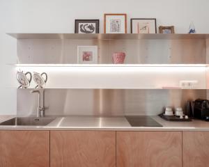 eine Küche mit einer Spüle aus Edelstahl und Holzschränken in der Unterkunft La Maison de Chestret in Lüttich