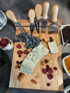 a wooden cutting board with blueberries and cheese and spoons at Leśne Niebo in Lubniewice
