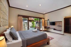 a bedroom with a large bed and a living room at Mahe Garden Inn and Villas by Kamara in Kuta