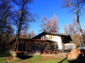 een huis in het bos met tafels en bomen bij Albergo Pineta in Castello di Fiemme