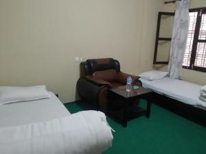 a room with two beds and a couch and a chair at Diya's Guest House in Bandīpur