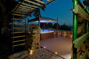 a deck with a hot tub under a pergola at night at Craigadam Lodge with Hot tub in Castle Douglas