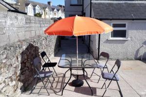 a table and chairs with an orange umbrella at Porthcawl House Near Beach With Extensive Parking in Porthcawl