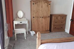 a bedroom with a dresser a mirror and a wooden cabinet at Porthcawl House Near Beach With Extensive Parking in Porthcawl