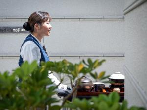 Eine Frau steht in einer Küche mit Töpfen und Pfannen in der Unterkunft Okinawa EXES Naha in Naha