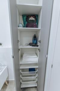 a closet with white shelves and towels at Your Cozy Sapphire Apartment in Athens