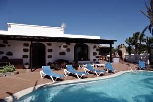 a swimming pool with blue chairs and a house at Casa Palmeral in Mácher