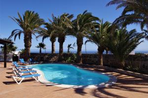 a swimming pool with two lounge chairs and palm trees at Casa Palmeral in Mácher