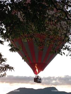 a red and white hot air balloon in the sky at Gaia Lake Bungalow, Kandalama in Dambulla