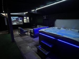 a dark room with a tub and a tv at Hot tub, 110Inch Outdoor Cinema, Fire Pit, 4 Acre garden, Luxury 5 Star Woodland Lodge in Skegness