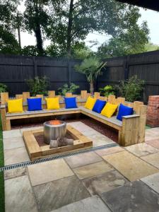 a bench with yellow and blue pillows and a fire pit at Hot tub, 110Inch Outdoor Cinema, Fire Pit, 4 Acre garden, Luxury 5 Star Woodland Lodge in Skegness