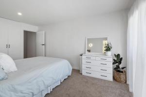 a white bedroom with a bed and a tv on a dresser at Peaceful Escape - Picton Holiday Apartment in Picton