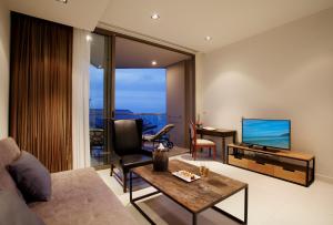 een woonkamer met een bank, een televisie en een tafel bij Pattaya Modus Beachfront Resort in Noord Pattaya