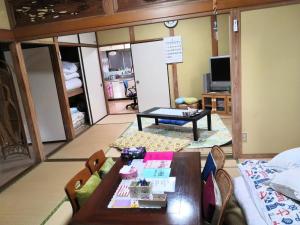 uma sala de estar com uma mesa e um sofá em shiokaze guest house / Vacation STAY 6794 em Matsuyama