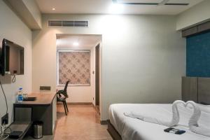 Hotel VR Grand في Vizianagaram: غرفة فندقية بسريرين ومكتب ونافذة