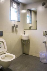 La salle de bains est pourvue de toilettes, d'un lavabo et d'un miroir. dans l'établissement Hotel VR Grand, à Vizianagram City