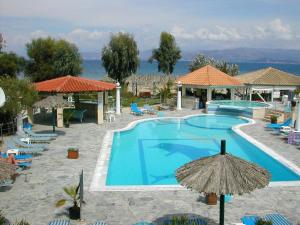 a swimming pool with umbrellas and chairs and the ocean at Sweet Dreams in Kavos