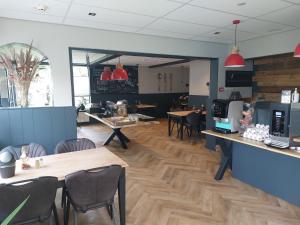 a restaurant with wooden tables and chairs and a counter at Hotel De Dennen in Egmond aan Zee