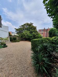 un jardin avec des buissons et des arbres et un bâtiment dans l'établissement LA PARENTHÈSE HAVRAISE - Parking privé Plein centre & Très calme, au Havre